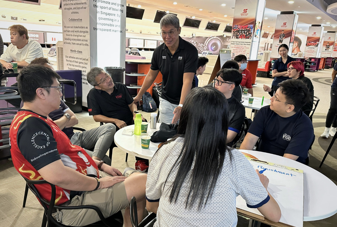 A group of people gathered around a table inside a store, engaged in conversation and sharing ideas.
